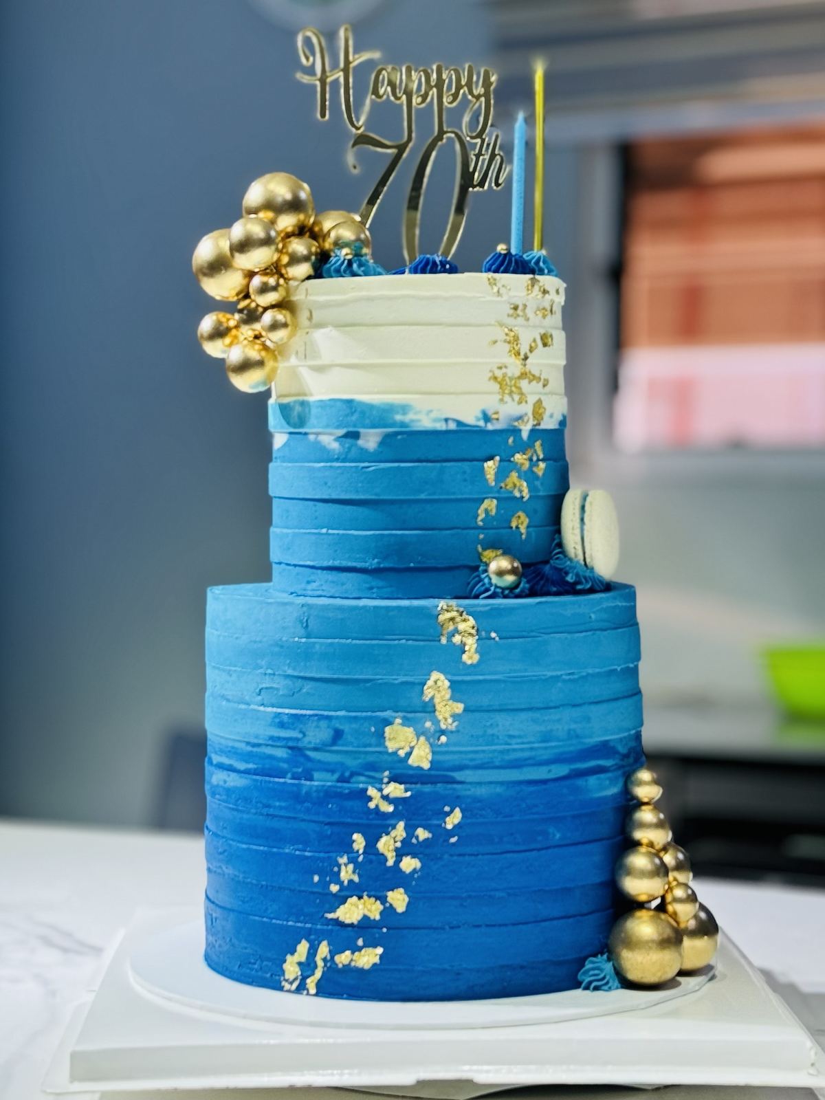 Blue ombre two-tier cake with gold leaf and gold sugar pearls for a 70th birthday
